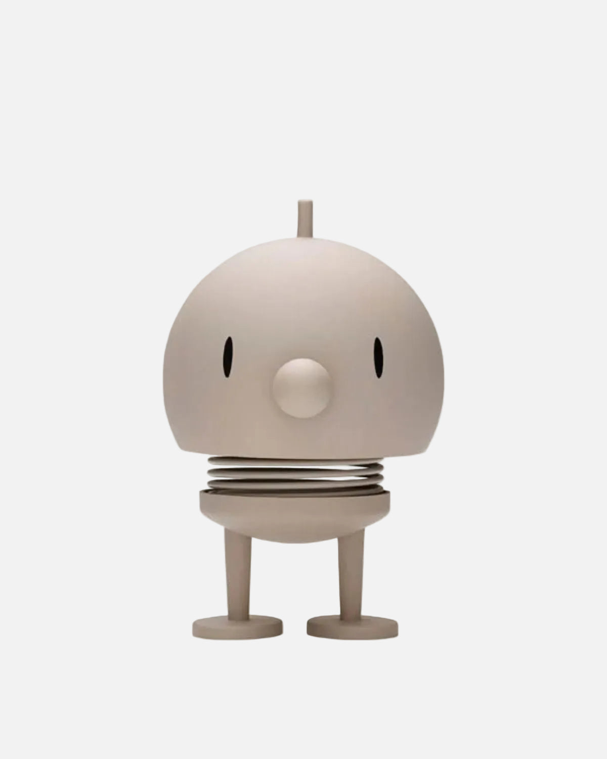 A minimalist, stylized robot figurine in a warm beige or cream color, featuring a rounded dome head with small black oval eyes, a circular nose, a spring-like ribbed waist, and two short legs on a plain white background.