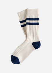 A pair of cream-colored ribbed crew socks with navy blue stripes near the cuff and navy blue toe caps, displayed on a clean white background.