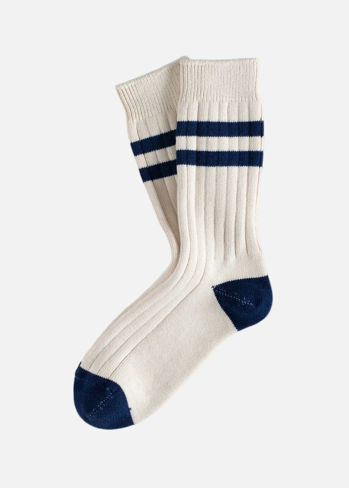 A pair of cream-colored ribbed crew socks with navy blue stripes near the cuff and navy blue toe caps, displayed on a clean white background.