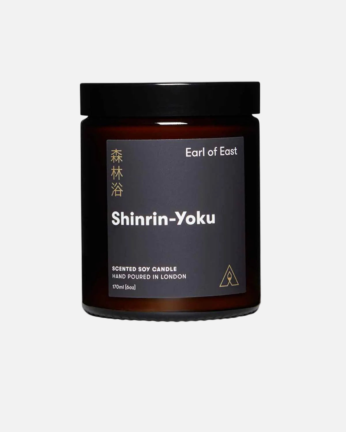An amber glass jar candle with a black lid and a dark charcoal label. The label features white and gold text, including the brand name 'Earl of East' and the scent name 'Shinrin-Yoku'.