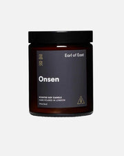 An amber glass jar candle with a black lid and a dark charcoal label. The label features the brand name 'Earl of East' and the scent name 'Onsen' in white text, with gold Chinese characters on the left side.