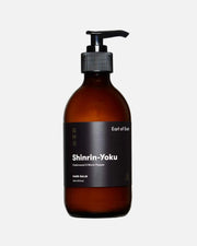 An amber glass pump bottle of Shinrin-Yoku Hand Balm by Earl of East, featuring a black label and black pump dispenser, set against a plain white background with a soft shadow.
