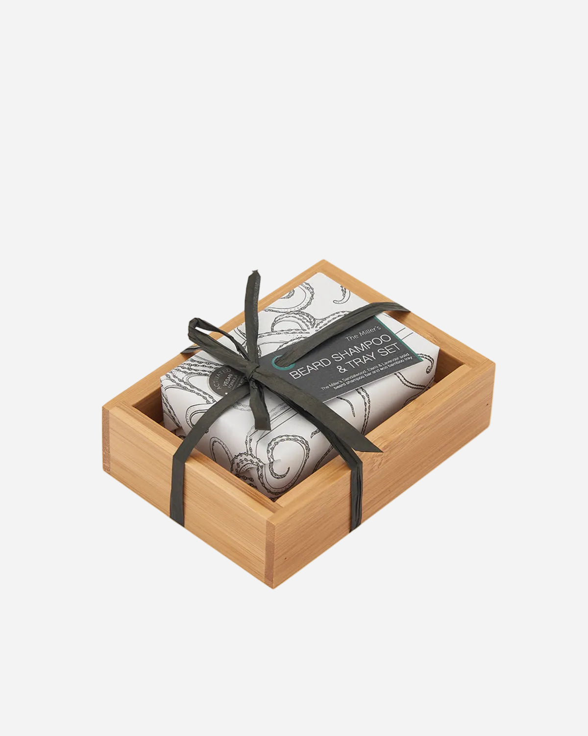 Two bars of soap in a wooden box with a black ribbon on a white background