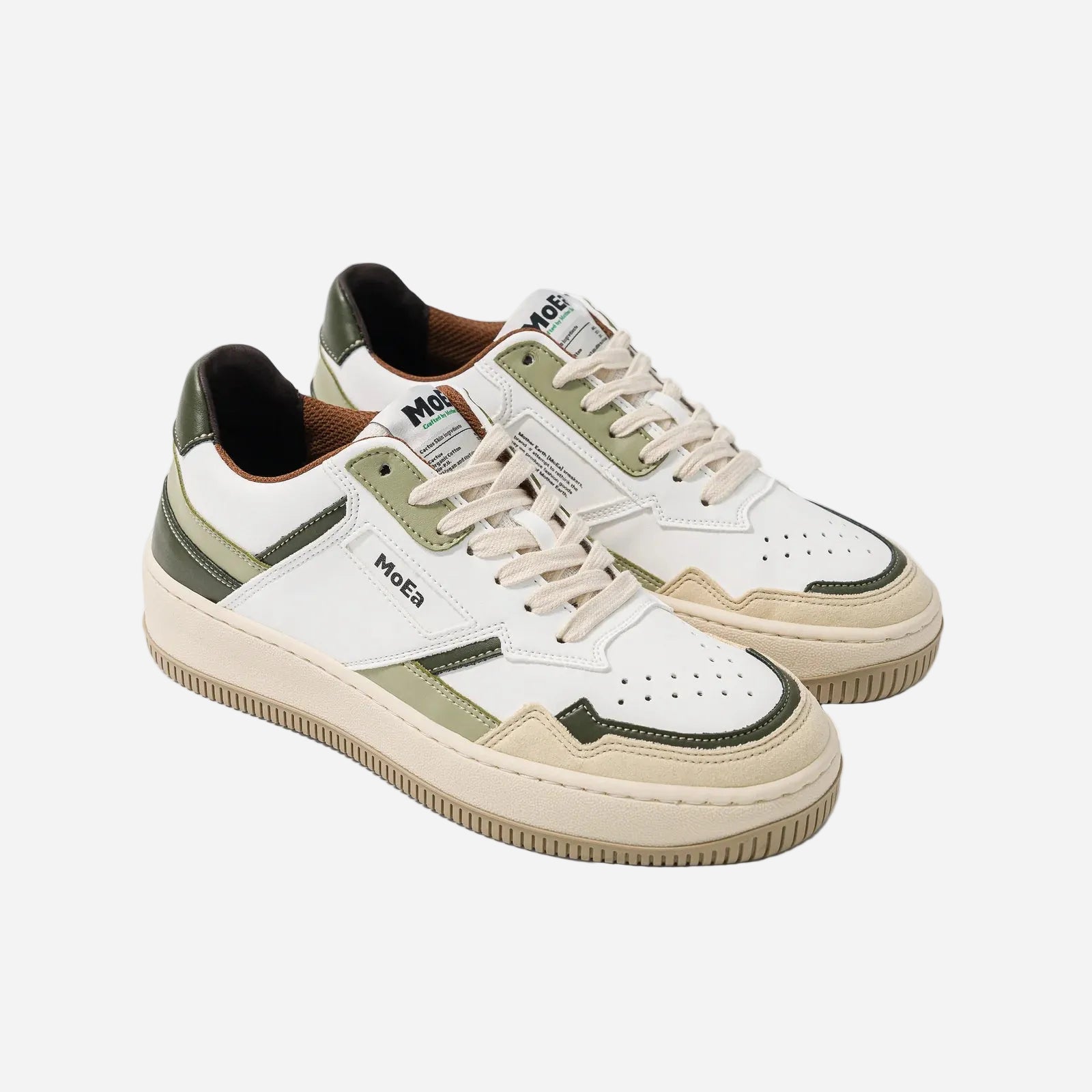 Pair of white and green sneakers with 'MOEA' branding on a light gray background