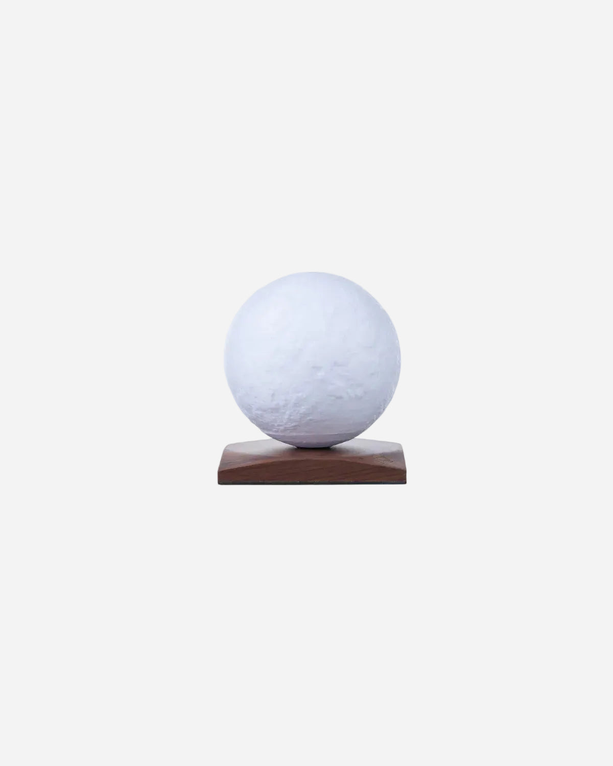 White moon shaped lamp on a wooden stand against a white background