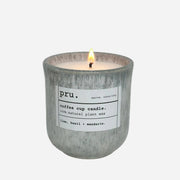 Candle in a textured container with a label on a light gray background