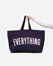 black tote bag with 'EVERYTHING' text held by a person on a white background