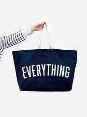 Navy tote bag with 'EVERYTHING' text held by a person on a white background