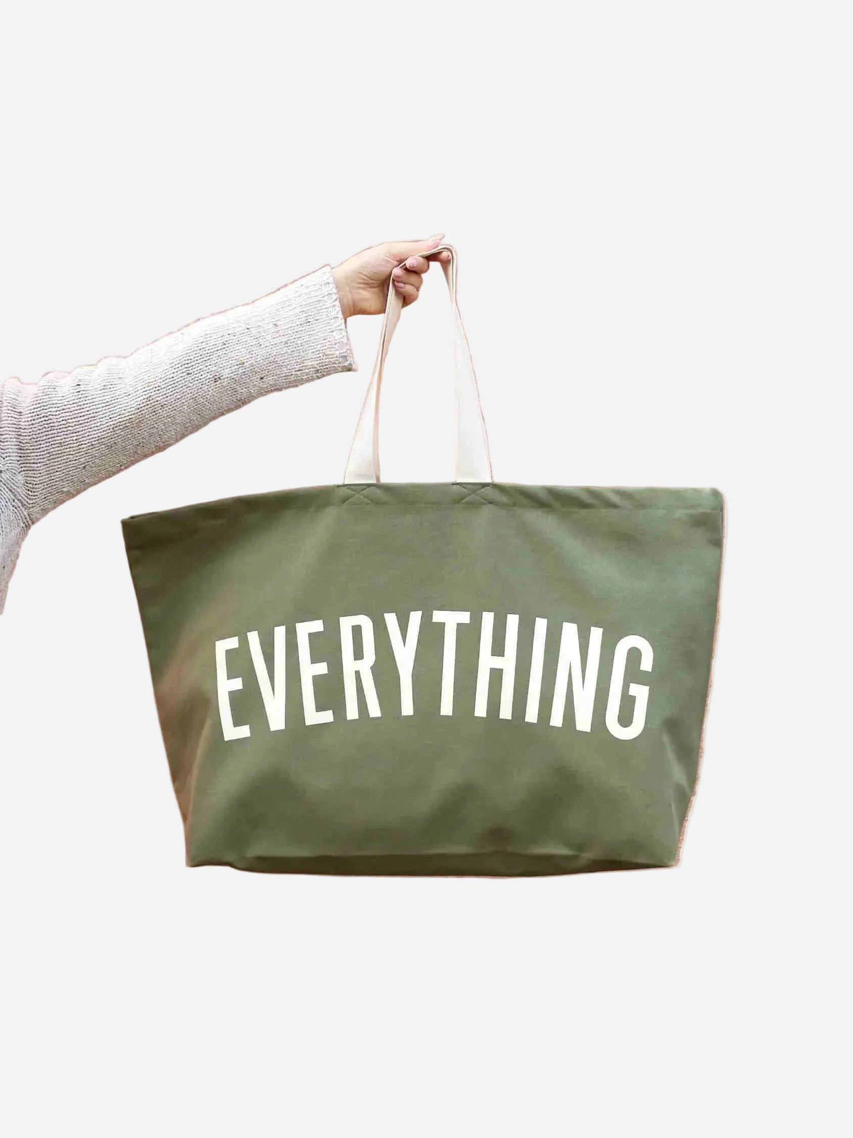 Green tote bag with 'EVERYTHING' text held by a person on a white background